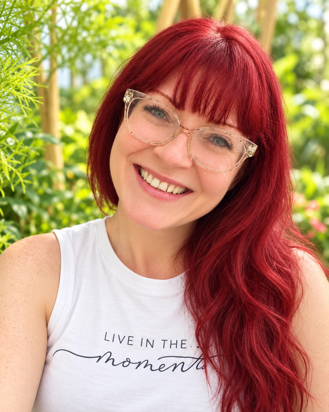 Wendy smiling among garden greenery wearing her Live in the Moment shirt